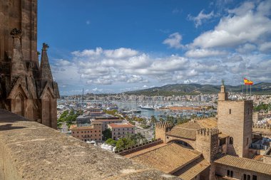 Ortaçağ Katedrali 'nin terasından Palma' lı Santa Maria Katedrali 'nin çatısından La Almudaina Kraliyet Sarayı' nın çatısından ve İspanyol bayrağının olduğu kuleden manzara. Arka planda İspanya 'nın Palma limanı.