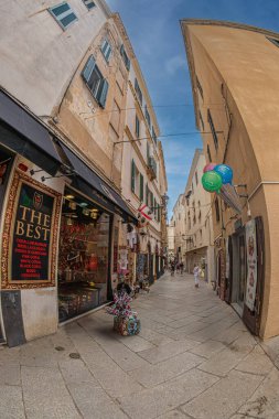 ALGHERO, İtalya - 3 Temmuz 2024: Geleneksel restoranları ve hediyelik eşya dükkanları olan tipik bir ortaçağ Sardinya caddesi.