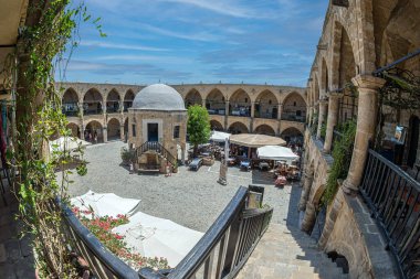 NICOSIA, CYPRUS - JUNE 18, 2024: Buyuk Han, the largest caravansarai on the island. It was built by the Ottomans in 1572. In courtyard is a mosque with a fountain courtyard cafes and souvenir shops. clipart