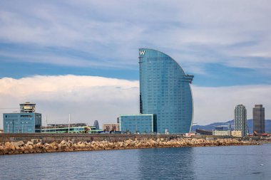 BARCELONA, SPAIN - APRIL 15, 2024: View from the sea with: Hotel W, Torre Mapfre, an office skyscraper; Hotel Arts, a luxury hotel and the El Peix d'Or, an fish sculpture designed by Frank Gehry. clipart