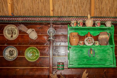 MURIGHIOL, ROMANIA - 20 Temmuz 2020: Romanya 'daki Lipova etnik grubunun tipik güzel halk nesneleriyle dekore edilmiş ahşap bir yemek odası duvarıyla iç mekan. Tuna Deltası.
