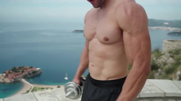Athlete Beautiful Body Large Muscles Raises His Hands Dumbbells Nature — стоковое видео