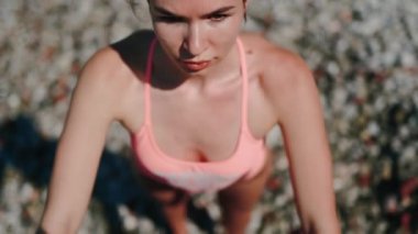 Güzel bir sahilde, doğası gereği güzelliklerle çevrili, sıcak güneş ışığı altında çalışan bir kadının yakın çekimi.