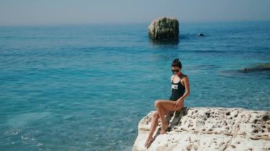 Huzurlu bir deniz kenarı anı başlıyor, resimli kayalık bir sahilde rahatlatıcı bir model sergileniyor.