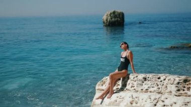 Bir kadın, güzel turkuaz denizde huzurlu bir anın tadını çıkarıyor. Huzur hissi veriyor.