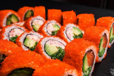 Lezzetli somonlu suşi dürümleri zarif, koyu bir tabakta sunulur. Her yerdeki yemek severleri ayırt etmek için mükemmeldir.