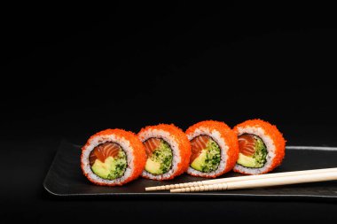 Lezzetli somonlu suşi dürümleri zarif, koyu bir tabakta sunulur. Her yerdeki yemek severleri ayırt etmek için mükemmeldir.