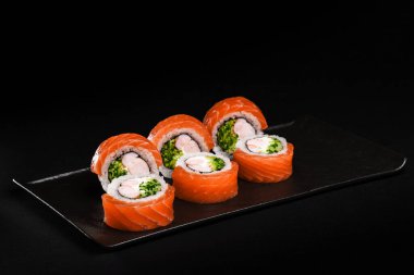 Lezzetli somonlu suşi dürümleri zarif, koyu bir tabakta sunulur. Her yerdeki yemek severleri ayırt etmek için mükemmeldir.