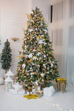 Christmas tree stands in middle of spacious room near sofa, panoramic window. New Year interior