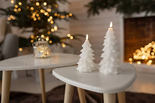 candle on table front of fireplace. New Year holiday or celebration, mood, stylish Christmas Scandinavian minimalist interior. Cozy house