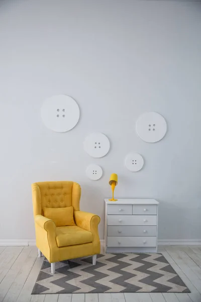 a yellow modern chair on the background of a white decorated wall with a beautiful carpet