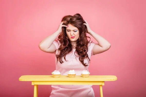 Close up of plus size redhead woman with bright makeup, sweet handmade donut cake. Studio color background, unusual emotion. Body positive, weight loss