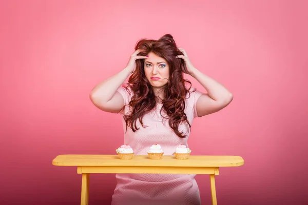 Close up of plus size redhead woman with bright makeup, sweet handmade donut cake. Studio color background, unusual emotion. Body positive, weight loss