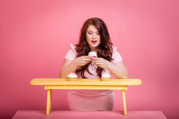 Close up of plus size redhead woman with bright makeup, sweet handmade donut cake. Studio color background, unusual emotion. Body positive, weight loss