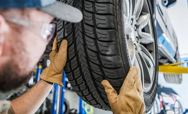 Seasonal Car Tires Change. Replacing Summer Tread to Winter Tread. Automotive Theme. Caucasian Car Service Worker Performing Scheduled Replacement.