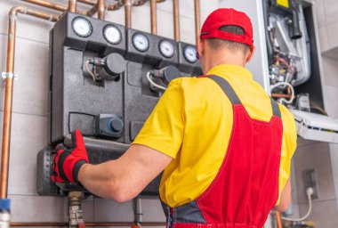 Profesyonel Bakım Teknisyeni Ticari Bina Mekanik Odasında Su Isıtma Kurulumunu Denetliyor.