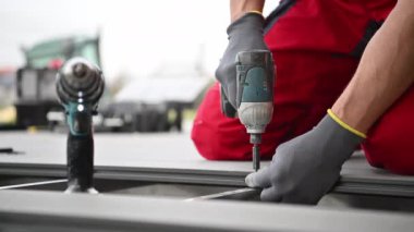 Construction Worker Installing Composite Patio Deck Floor Attaching Elements Using Cordless Drill Driver. Industrial Theme.