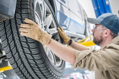 Professional Mechanic Preparing to Remove the Rear Wheel From the Car During the Seasonal Tire Change. Automobile Service Theme.