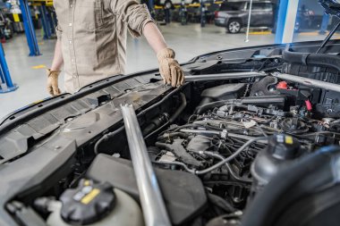 Car Mechanic Performing Engine Check on a Vehicle with the Hood Open. Professional Automobile Service. Automotive Theme.