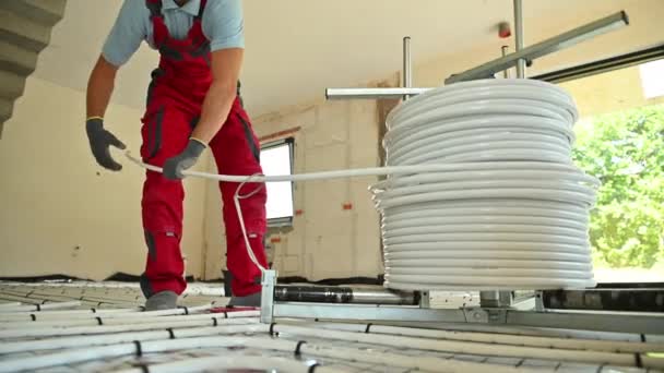 Professional Caucasian Hvac Worker Rolling Radiant Floor Heating Plastic Pipeline — Vídeo de Stock