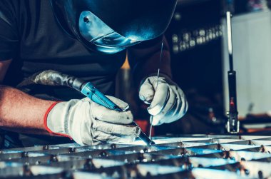 Closeup of Professional Welder in Protective Helmet Performing TIG Welding. Industrial Production and Manufacturing Theme.