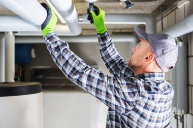 Professional Plumber Checking Water Valves in the Pipes of the Residential House Heating System.