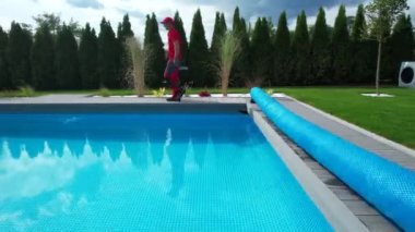 Outdoor Residential Swimming Pool Maintenance. Technician Walking Along the Poolside.