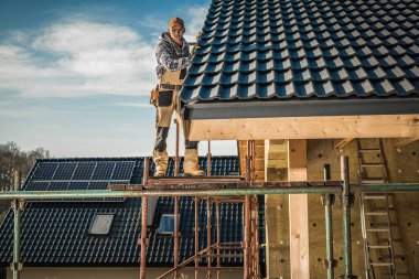 Professional Contractor Working on Roof Installation at Residential House Construction Site. Industrial Theme.