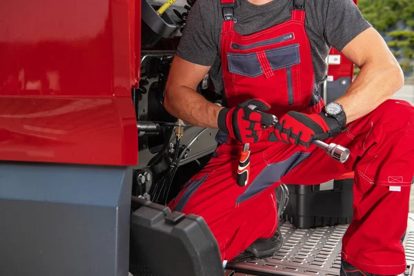 Closeup of Heavy Duty Vehicle Mechanic with Professional Tools in His Hands Fixing Semi Truck Tractor. Transportation Theme.