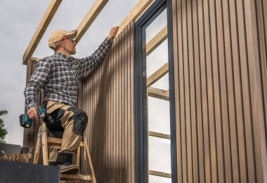 Modern Bahçe Bahçesi Kulübesi 'nde Kablosuz Matkap Şoförü ile deneyimli beyaz işçi. Bileşik Malzeme Duvarları.