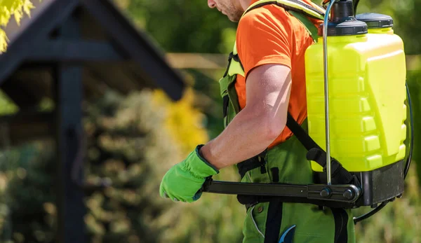 季節の害虫駆除治療中に背中に黄色いポンプスプレーを運ぶ専門庭師の閉鎖 農業のテーマ — ストック写真