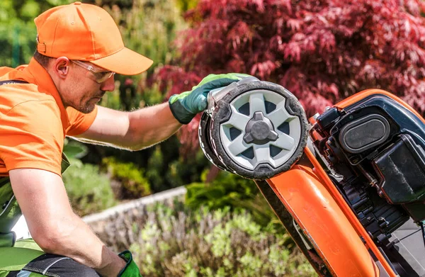 ガソリン草刈り機の問題 庭師は彼の芝刈り機で潜在的な問題を探しています 造園産業のテーマ — ストック写真