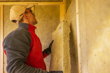 Profesyonel İnşaat İşçisi Mineral Yün Malzemeleri ile Binayı İzole Ediyor. Endüstriyel Tema.