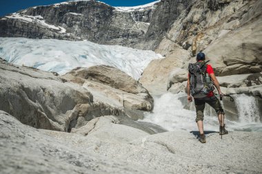 Sırt çantalı beyaz turist yaz yürüyüşü sırasında karla kaplı Rocky Dağı 'na bakıyor. Açık hava etkinlik temasıName.