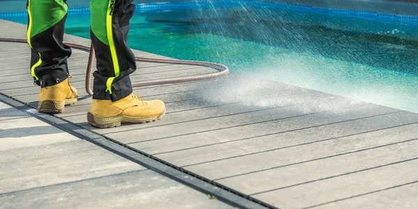 Man Cleaning His Poolside Deck with a Water. Swimming Pool Area Maintenance.