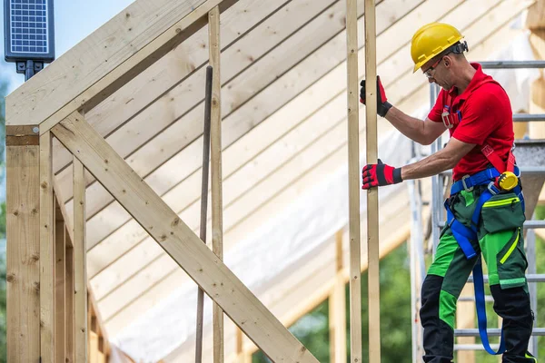 stock image Wooden House Skeleton Frame Construction Worker in His 40s on the Newly Built Roof Frame