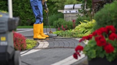 Ev sahibi bahçesindeki kiri temizliyor beton tuğla yolları baskı makinesiyle yıkıyor.