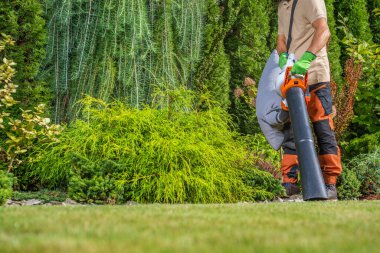 Beyaz adam 40 'lı yaşlarında. Bahçesini temizliyor. Süpürgeyle.