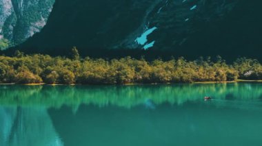 Norveç 'teki Buzul Lovatnet Gölü' nü geçen Red Canoe 'daki beyaz adam. Güneşli Norveç Gününün tadını çıkarıyorum.