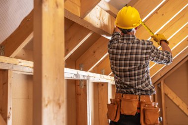 İnşaat Müteahhiti Ahşap Çerçeve Yapısı içinde Ölçüm alıyor. İnşaat Sitesi TemasıName.