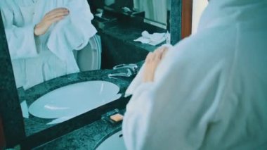 40 'lı yaşlarda beyaz bir adam otel banyosunda ellerini yıkıyor.