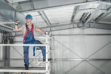 İskeleyi kullanarak Depo İnşaat Uzmanı İnceleme. HVAC Denetimi.
