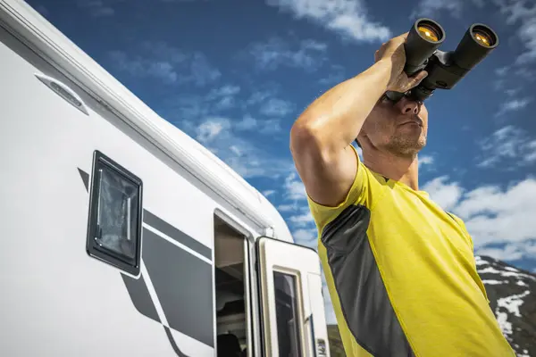 Caucasian Man Spotting Wildlife Using Binoculars While Camper Van Road Stock Photo