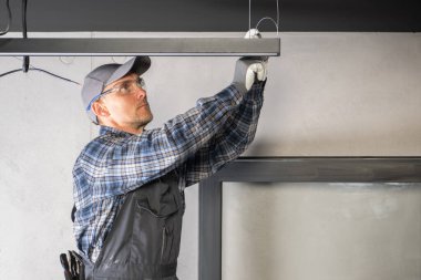 Kafkas İnşaat Müteahhiti Elektrikçi Askıya alınmış Işıklandırma Elementini Kuruyor
