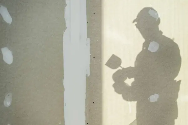 労働者の影を用いた内装パッチングテーマを構築する 建設業のテーマ ロイヤリティフリーのストック画像