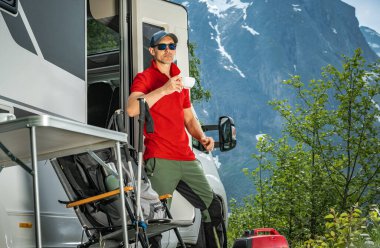 Caucasian Man in His 40s Spending His Vacations in a Camper Van He Own. Scenic Norwegian Nature. clipart