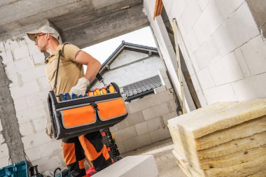 Omzunda bir alet kutusu asılı olan Kafkas Profesyonel İnşaat İşçisi. İnşaat Sitesi TemasıName.