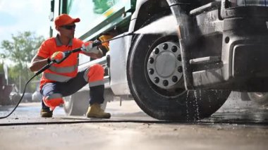 Atık Toplama Aracı Beyaz Sürücüsü Çöp Tedavi Tesisindeki Basınç Yıkama Makinesi ile yıkıyor.