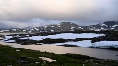 Eriyen Karla kaplı Dağlık Arazi Bulutlu. Norveç Dağları manzarası. Doğa Teması.