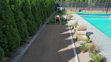 Kafkas bahçıvanı arka bahçedeki yüzme havuzunda çim biçiyor. Profesyonel Peyzaj Bahçe TemasıName.